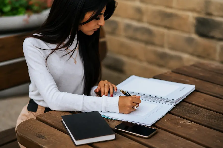 Mulher jovem escrevendo em caderno avaliando decisão de carreira como babá