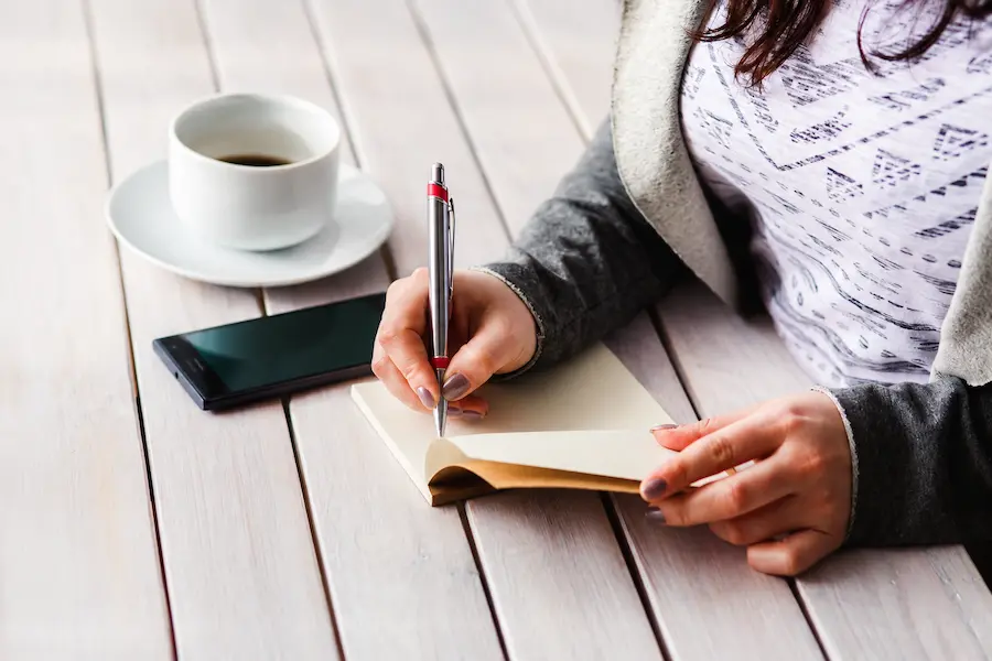 Mulher anotando contatos de emergência em caderno na primeira semana de trabalho