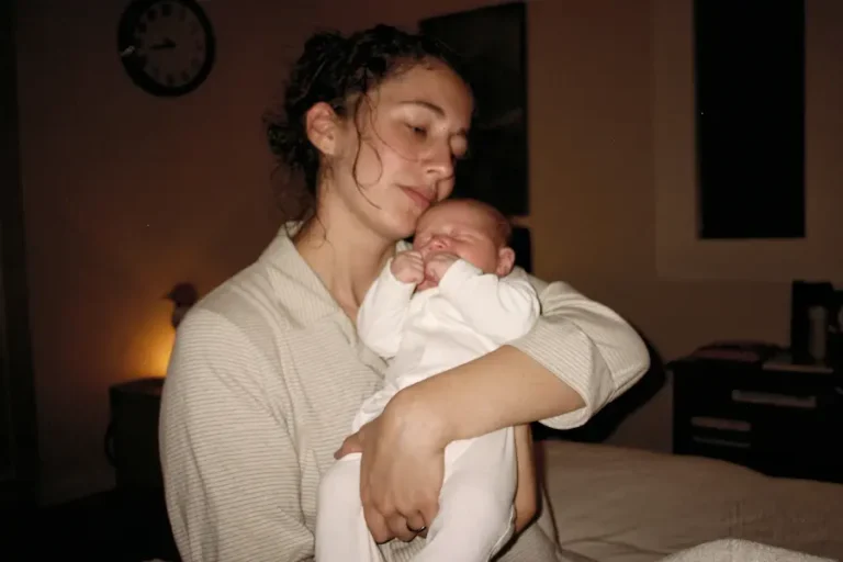 Mãe segurando bebê recém-nascido no colo durante a madrugada para acalmar choro de cólica